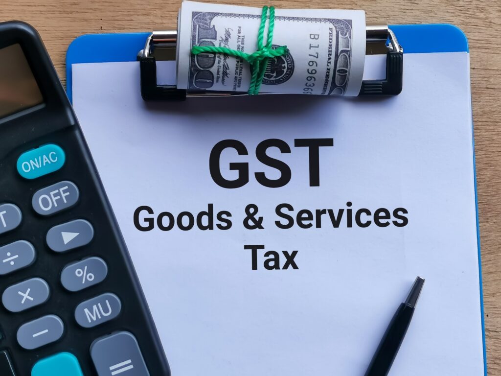 Phrase GST GOODS AND SERVICES TAX written on paper clipboard
